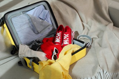 Photo of Open suitcase with traveler's belongings on bed