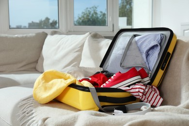 Open suitcase with traveler's belongings on bed