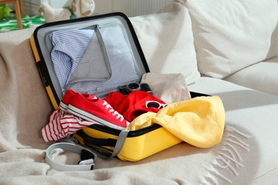 Photo of Open suitcase with traveler's belongings on bed