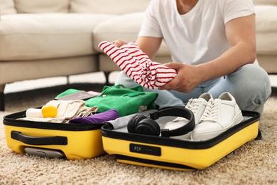 Man packing suitcase on floor at home, closeup