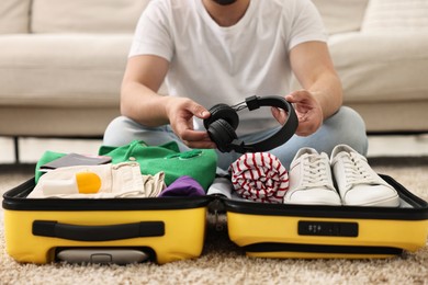 Photo of Man packing suitcase on floor at home, closeup