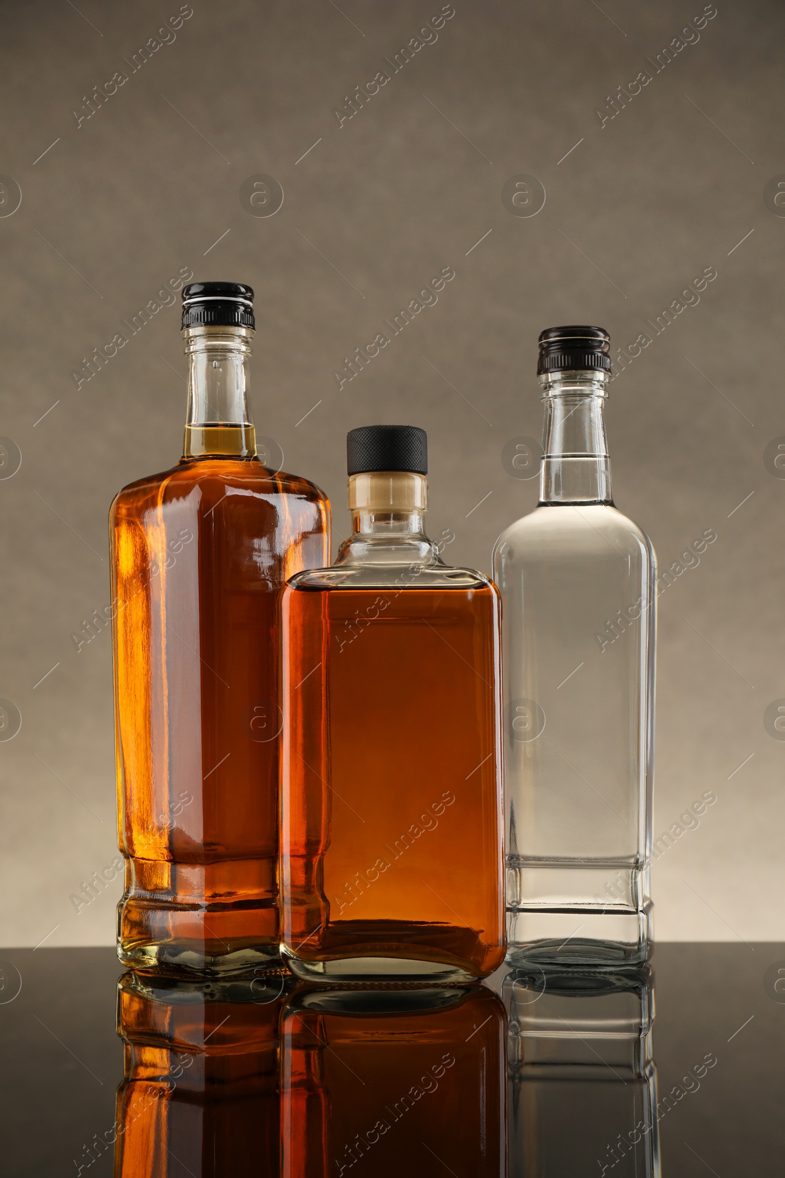 Photo of Bottles of different alcoholic drinks on table against gray background