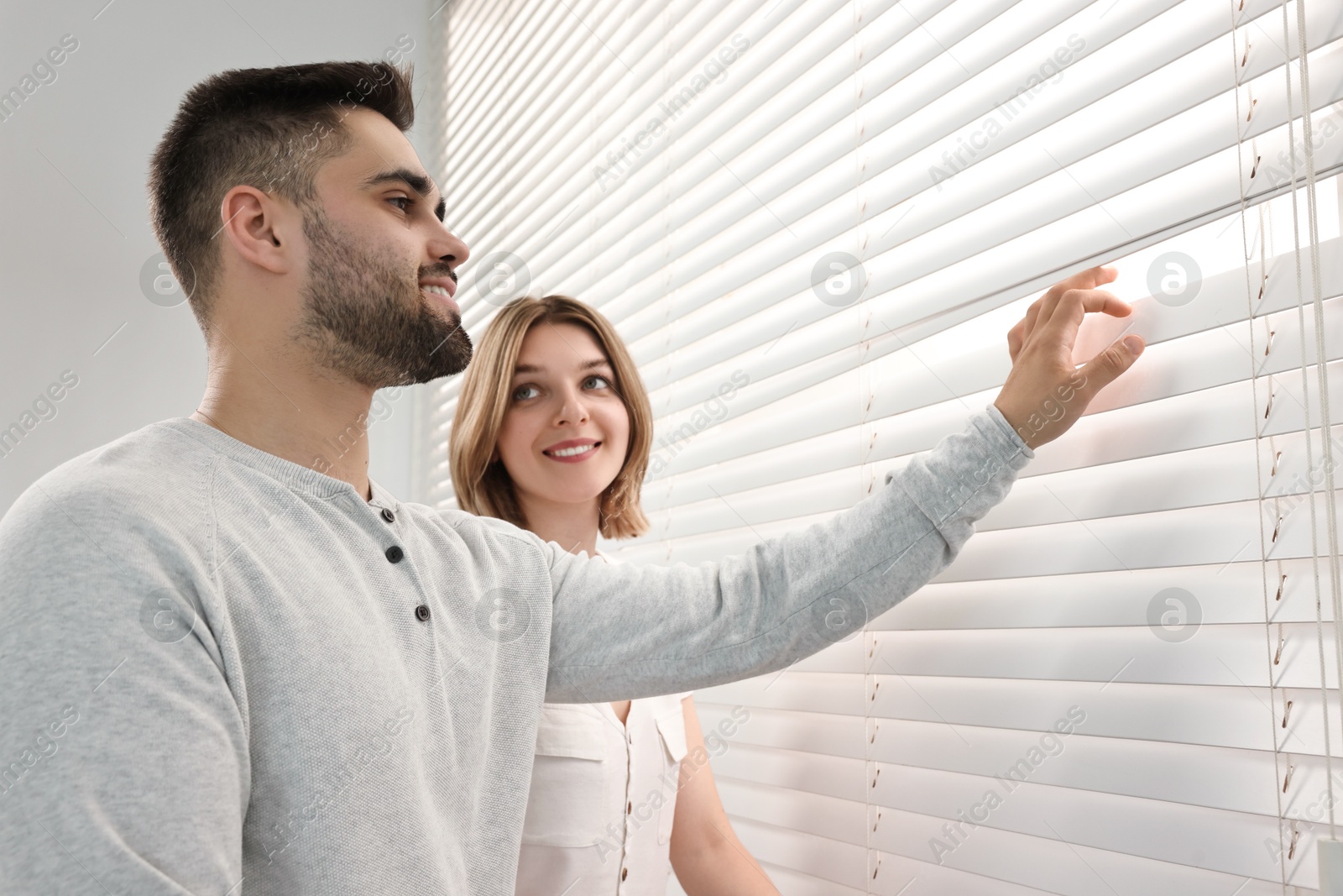 Photo of Young couple near window blinds at home