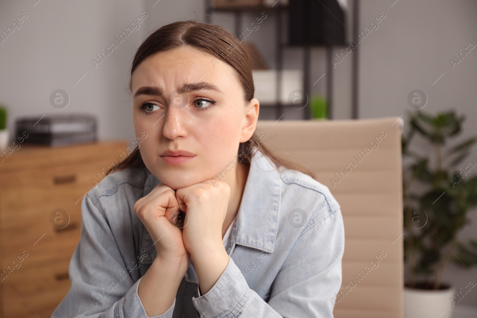 Photo of Embarrassed woman in denim jacket in office