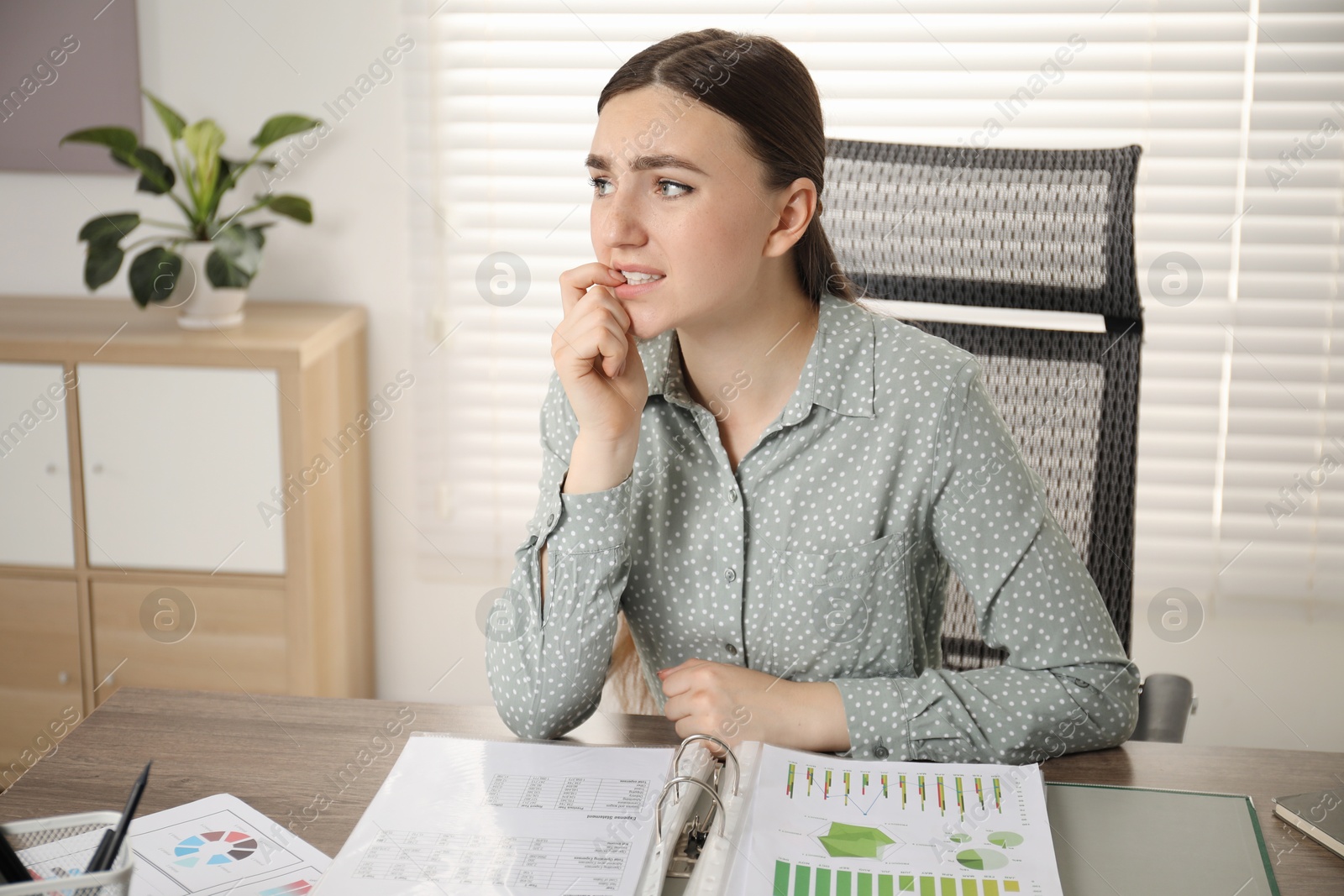 Photo of Embarrassed woman at wooden table with documents in office