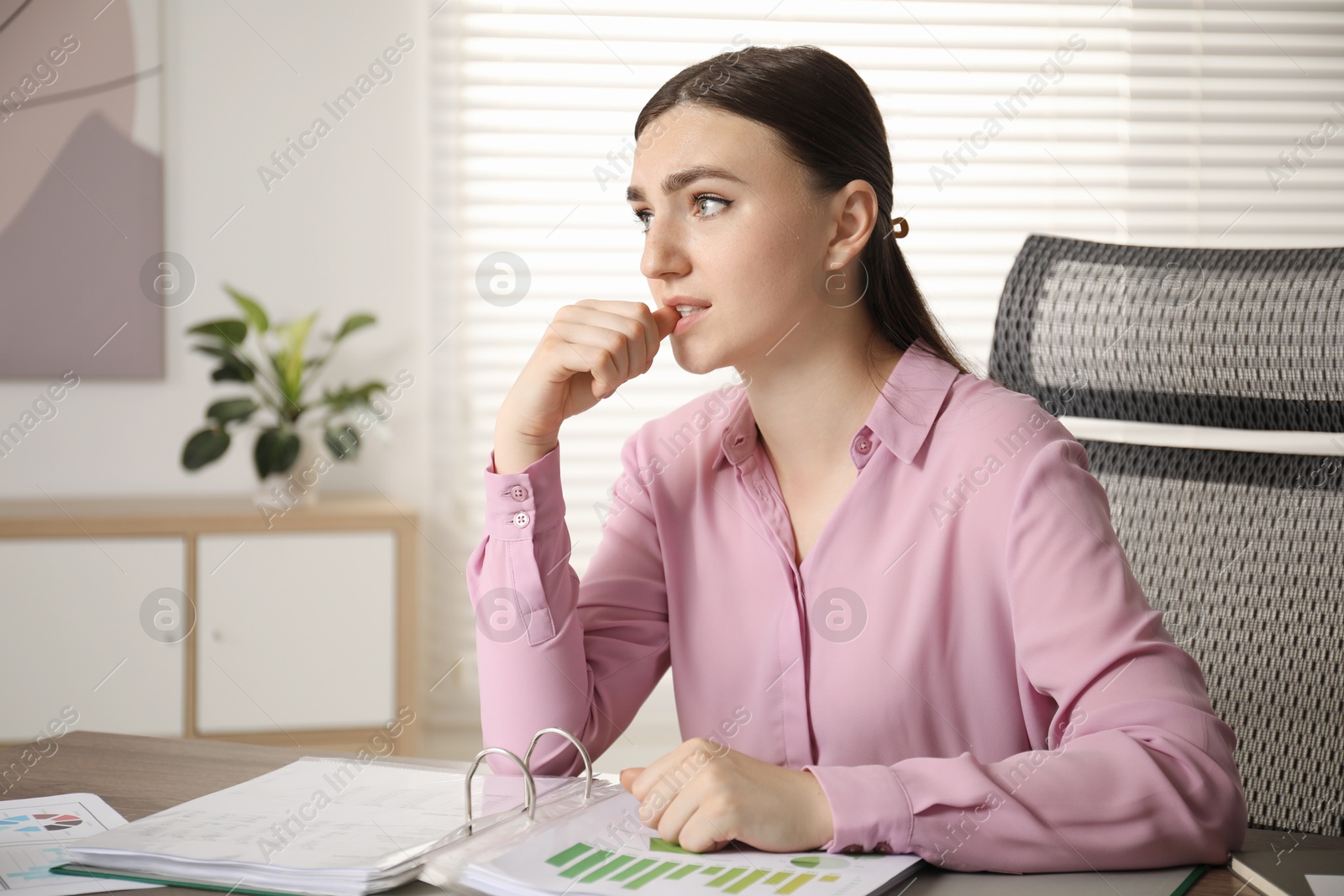 Photo of Embarrassed woman at table with documents in office, space for text