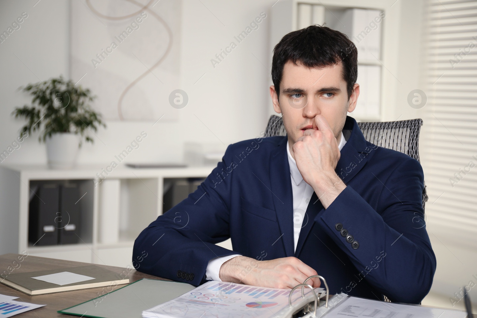 Photo of Embarrassed man at table with documents in office. Space for text