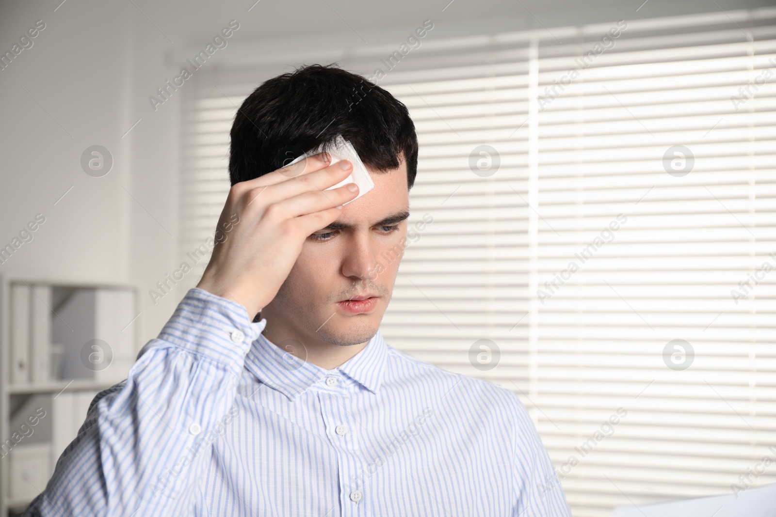 Photo of Embarrassed man with tissue in office, space for text