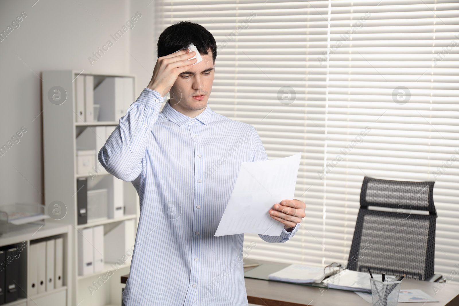 Photo of Embarrassed man with tissue and document in office