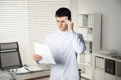 Photo of Embarrassed man with tissue and document in office