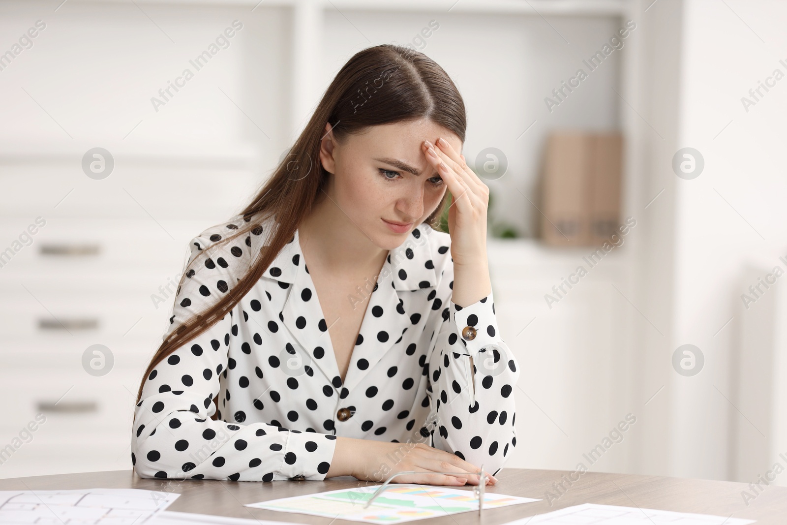 Photo of Embarrassed young woman at table in office