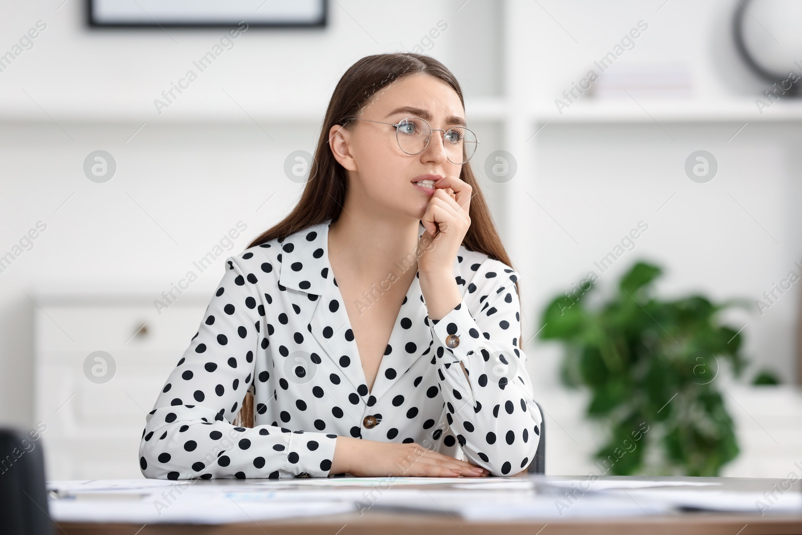 Photo of Embarrassed woman in glasses at table in office