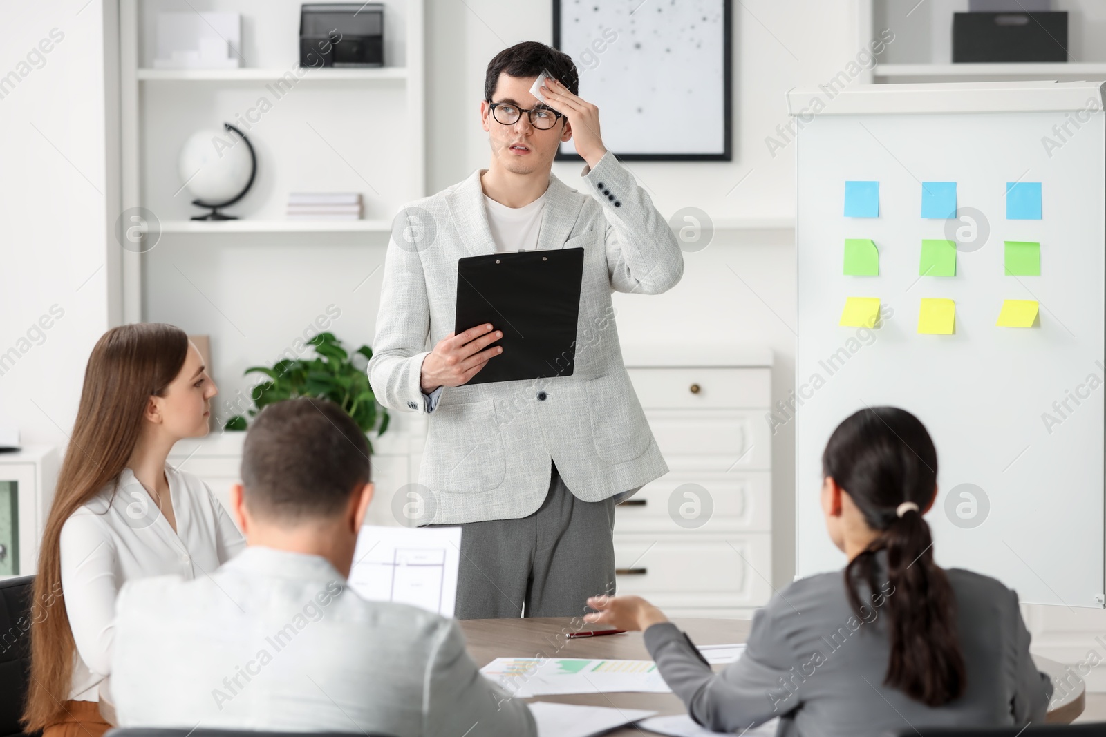 Photo of Man with clipboard feeling embarrassed during business meeting in office