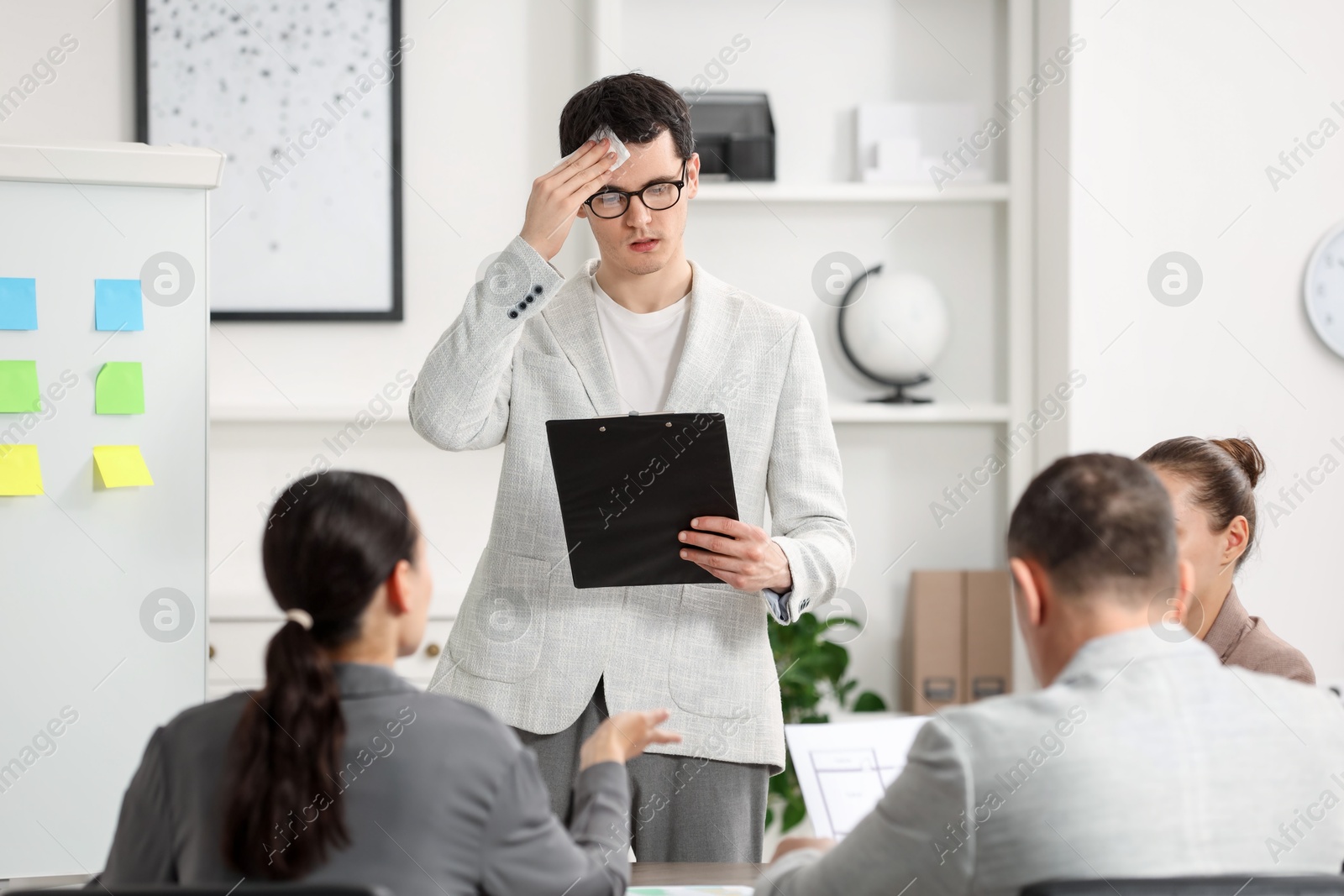 Photo of Man with clipboard feeling embarrassed during business meeting in office