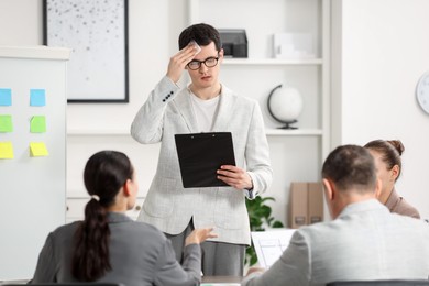Photo of Man with clipboard feeling embarrassed during business meeting in office
