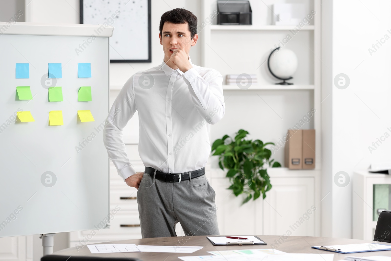 Photo of Embarrassed man near white board with sticky notes in office