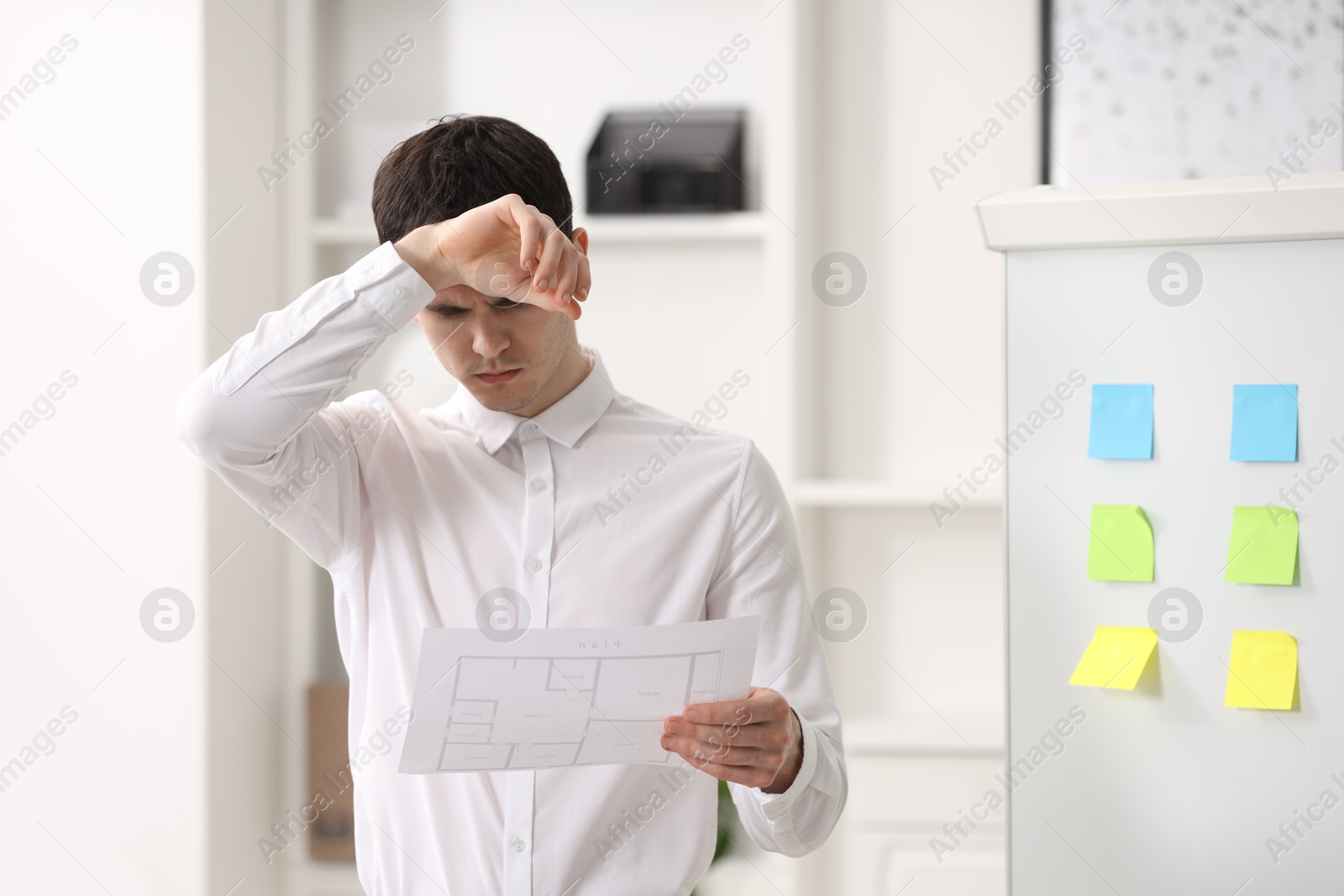 Photo of Embarrassed man with document near white board in office