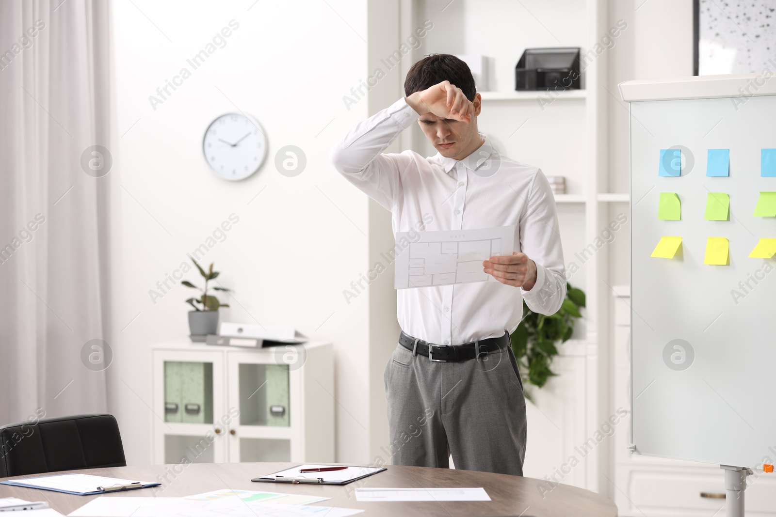 Photo of Embarrassed man with document near white board in office