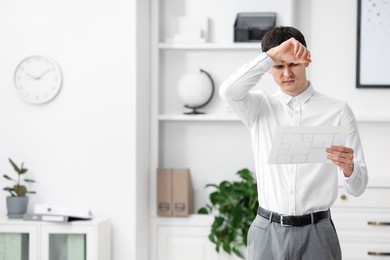 Photo of Embarrassed man with document in office, space for text