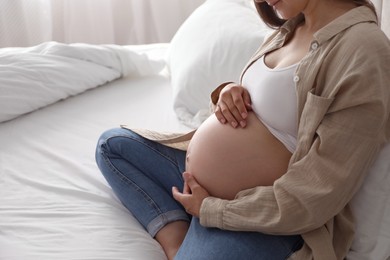 Photo of Beautiful pregnant woman on bed at home, closeup