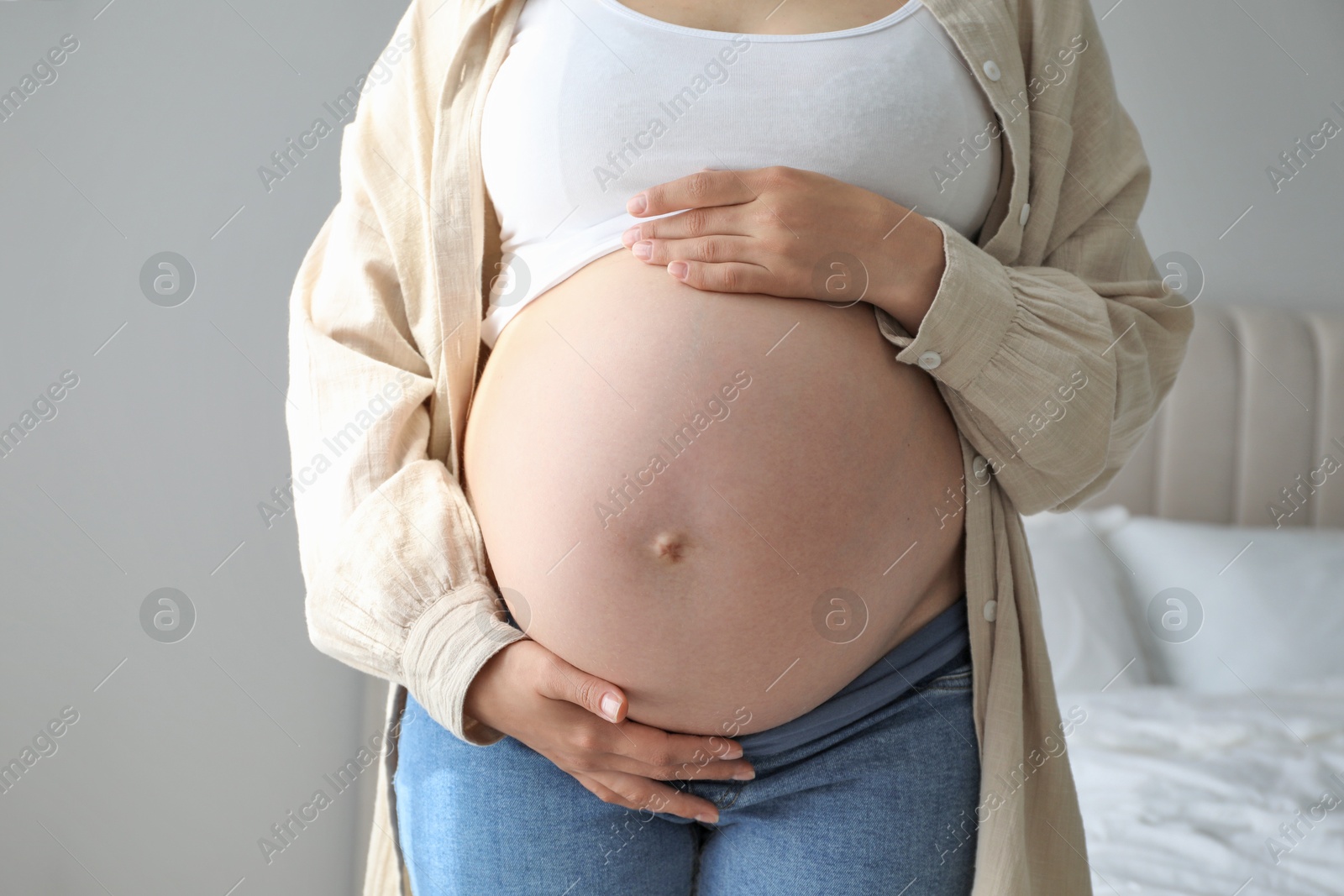 Photo of Pregnant woman in beige shirt at home, closeup