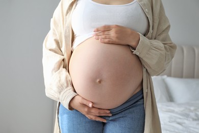 Pregnant woman in beige shirt at home, closeup