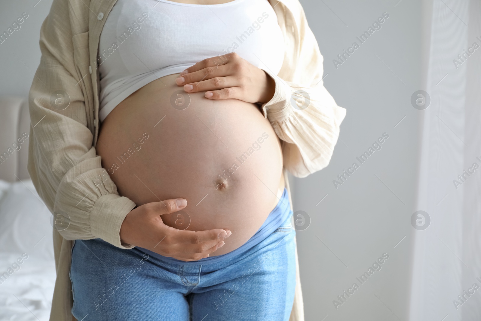 Photo of Pregnant woman in beige shirt at home, closeup