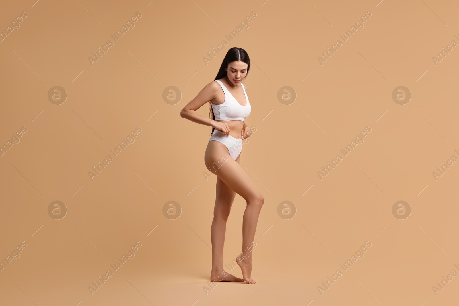 Photo of Beautiful woman with perfect skin in underwear posing on beige background. Body care