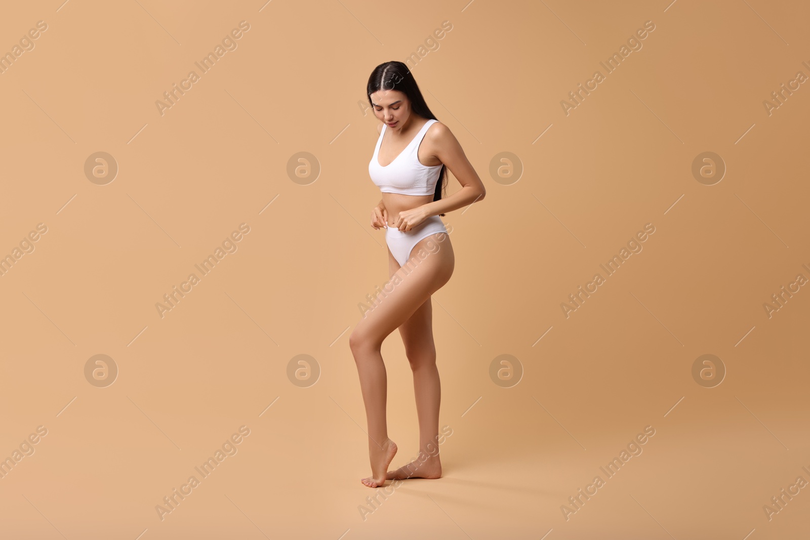 Photo of Beautiful woman with perfect skin in underwear posing on beige background. Body care