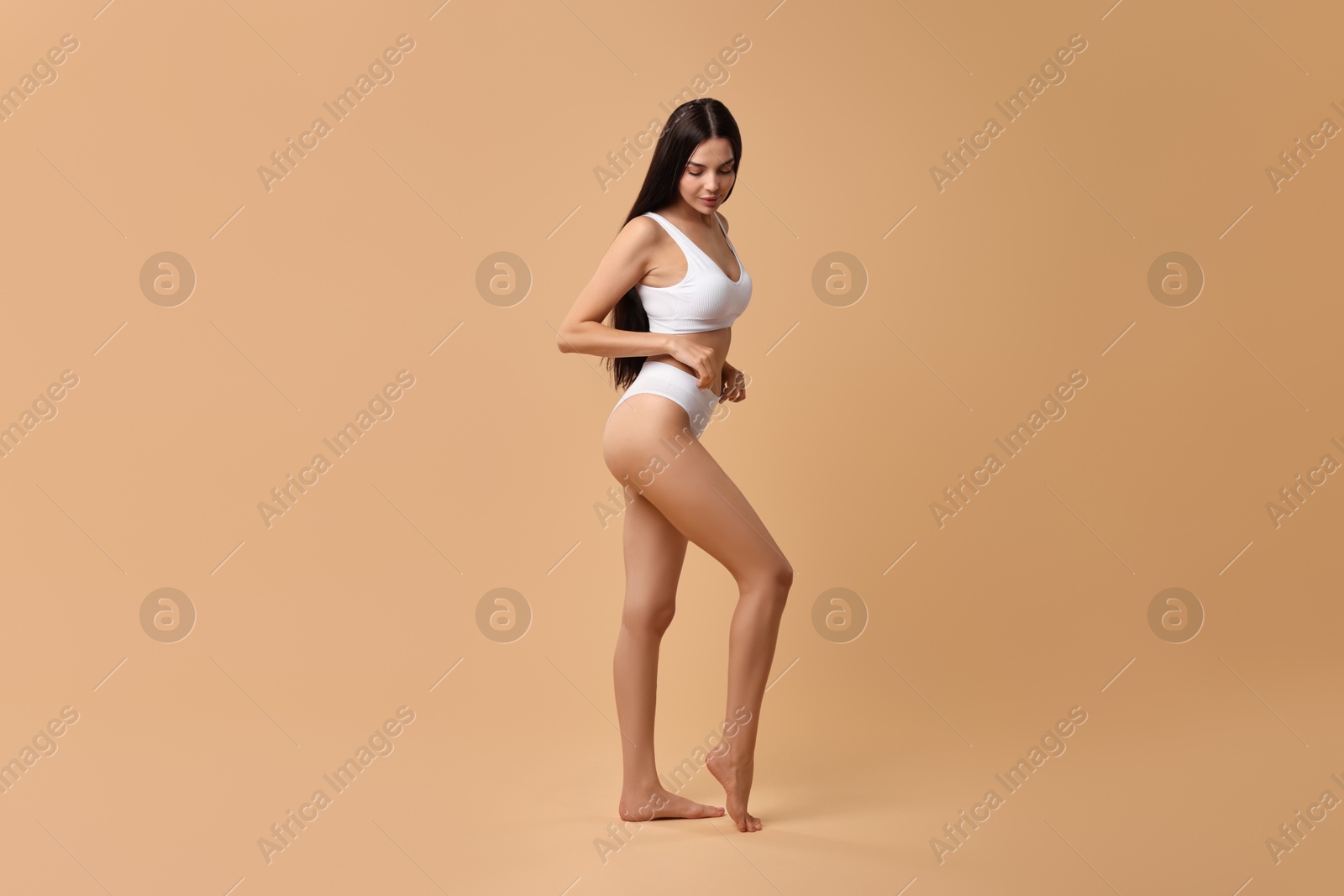 Photo of Beautiful woman with perfect skin in underwear posing on beige background. Body care