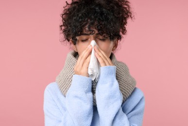 Photo of Cold symptom. Young woman with tissue on pink background