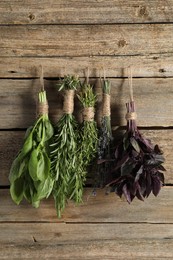 Bunches of different aromatic herbs hanging on rope near wooden wall