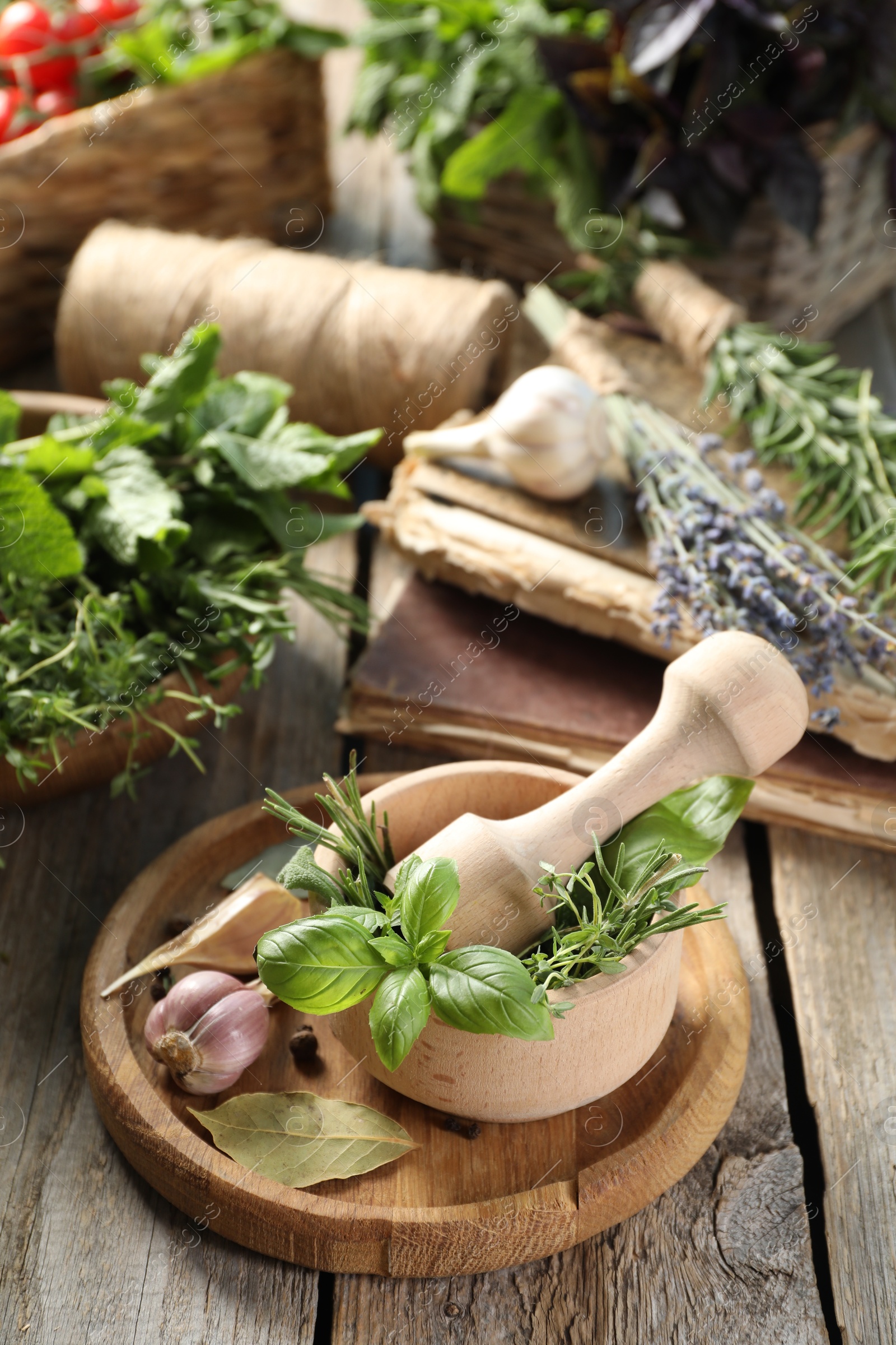 Photo of Different aromatic herbs, mortar with pestle and spices on wooden table