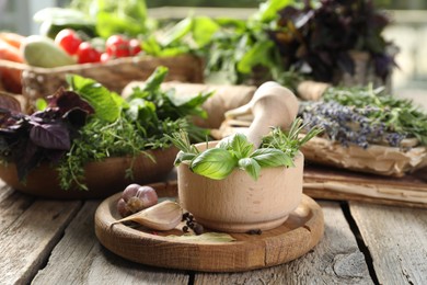 Photo of Different aromatic herbs, mortar with pestle and spices on wooden table, closeup