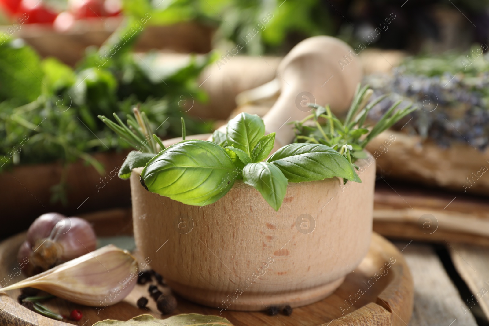 Photo of Different aromatic herbs, mortar with pestle and spices on wooden table, closeup