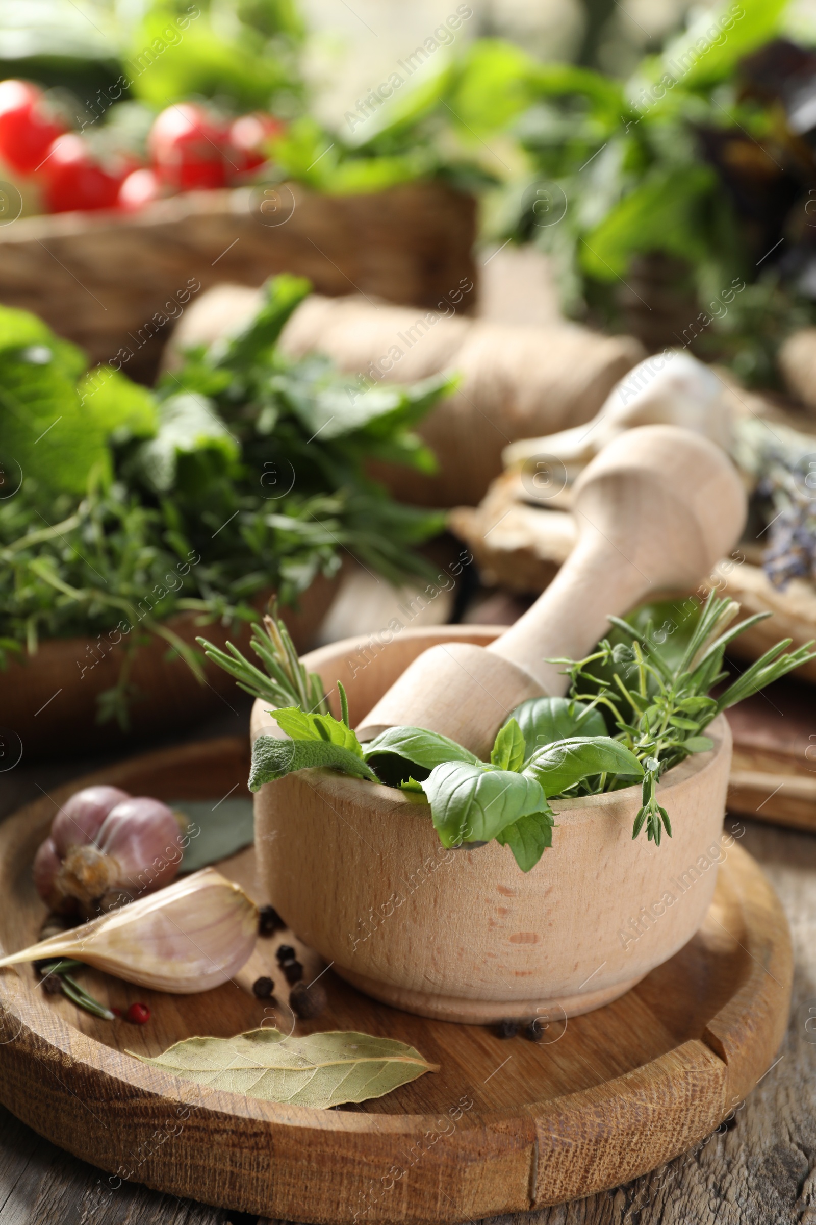 Photo of Different aromatic herbs, mortar with pestle and spices on wooden table, closeup