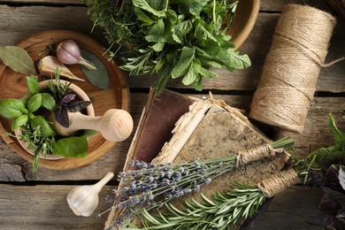 Different aromatic herbs, mortar with pestle, thread and spices on wooden table, flat lay