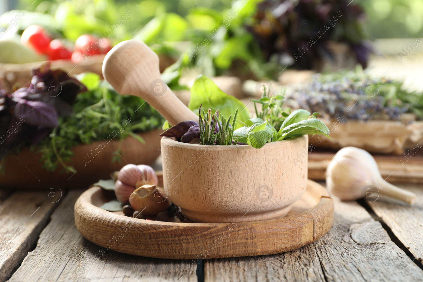 Photo of Different aromatic herbs, mortar with pestle and spices on wooden table, closeup