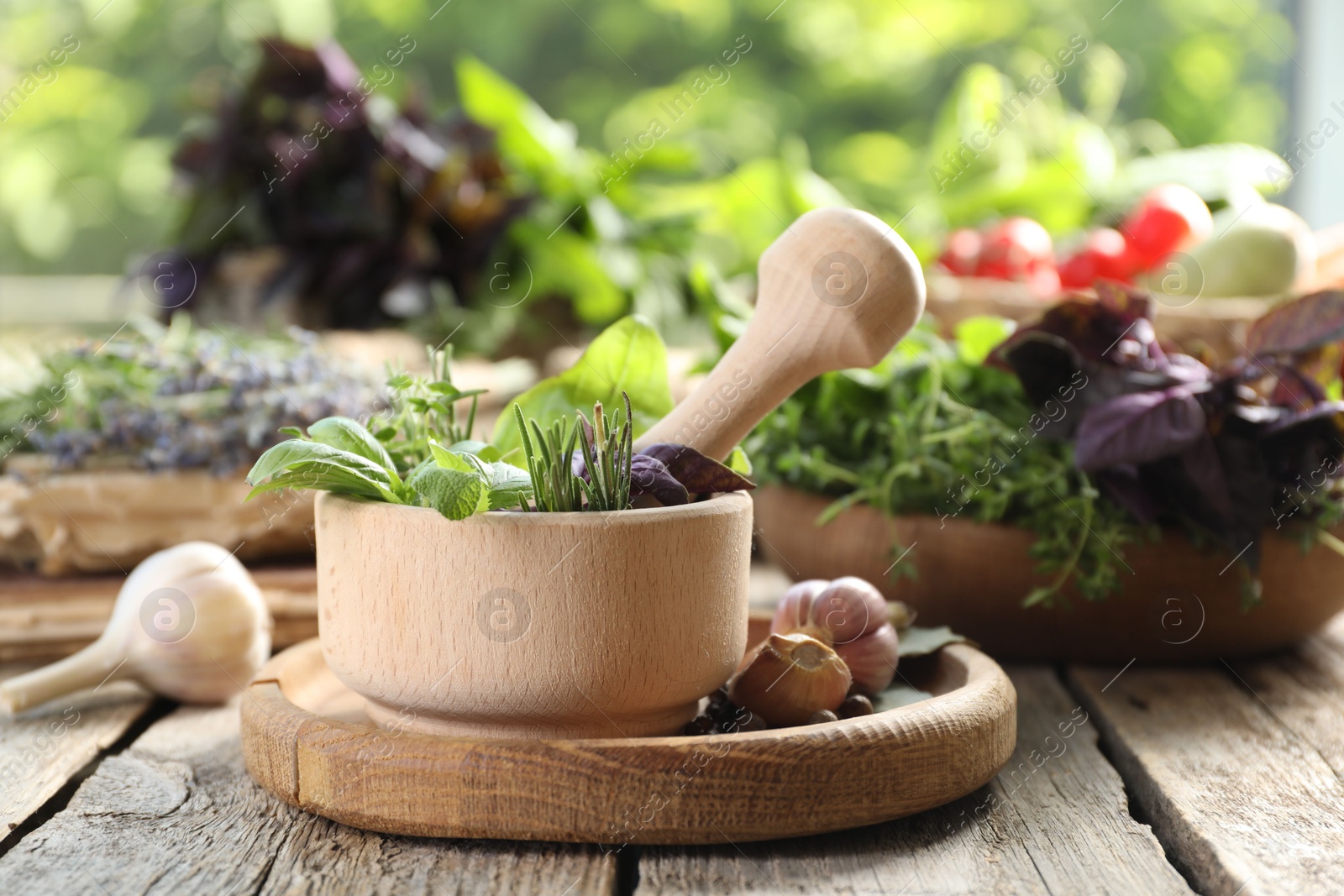 Photo of Different aromatic herbs, mortar with pestle and spices on wooden table, closeup