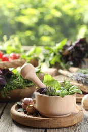 Photo of Different aromatic herbs, mortar with pestle and spices on wooden table, closeup