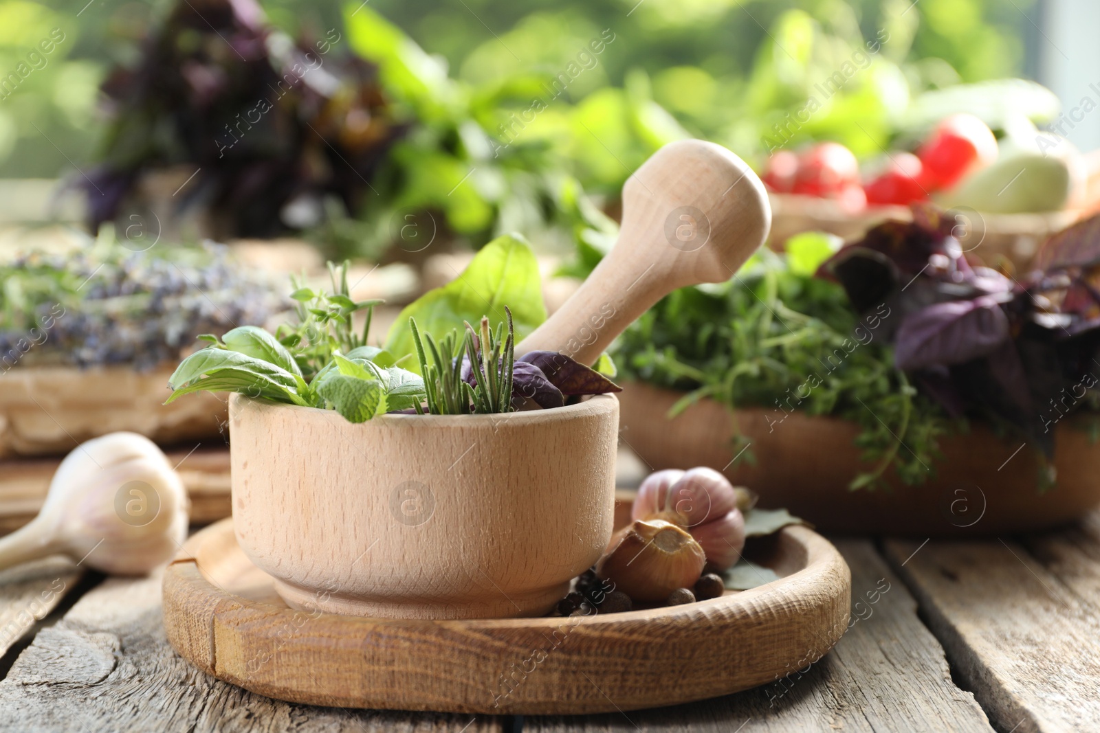 Photo of Different aromatic herbs, mortar with pestle and spices on wooden table, closeup