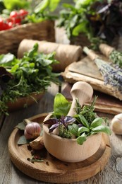 Photo of Different aromatic herbs, mortar with pestle and spices on wooden table, closeup