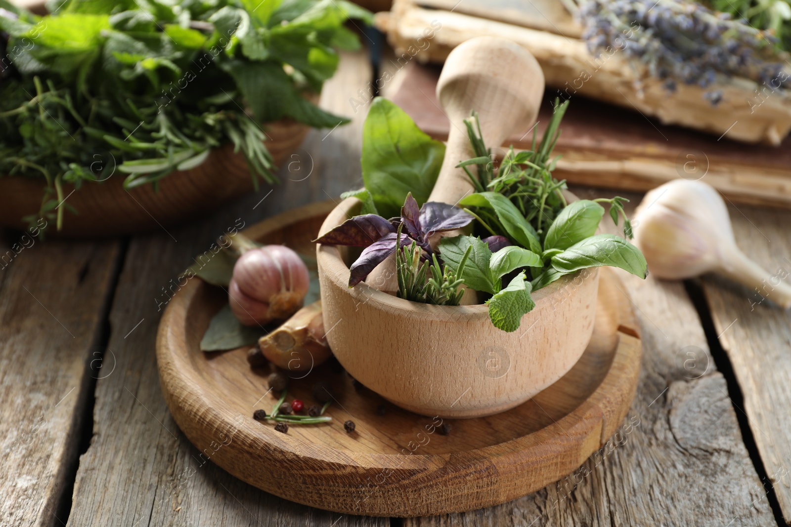 Photo of Different aromatic herbs, mortar with pestle and spices on wooden table, closeup