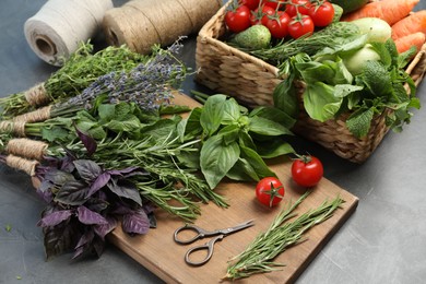 Different aromatic herbs, vegetables and scissors on gray table, closeup