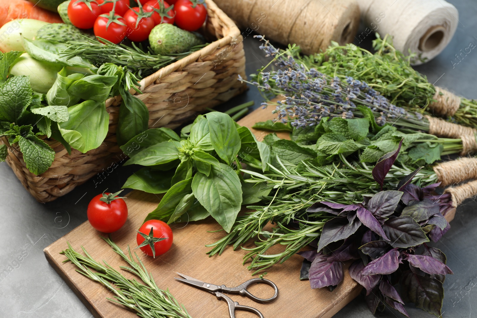 Photo of Different aromatic herbs, vegetables and scissors on gray table, closeup