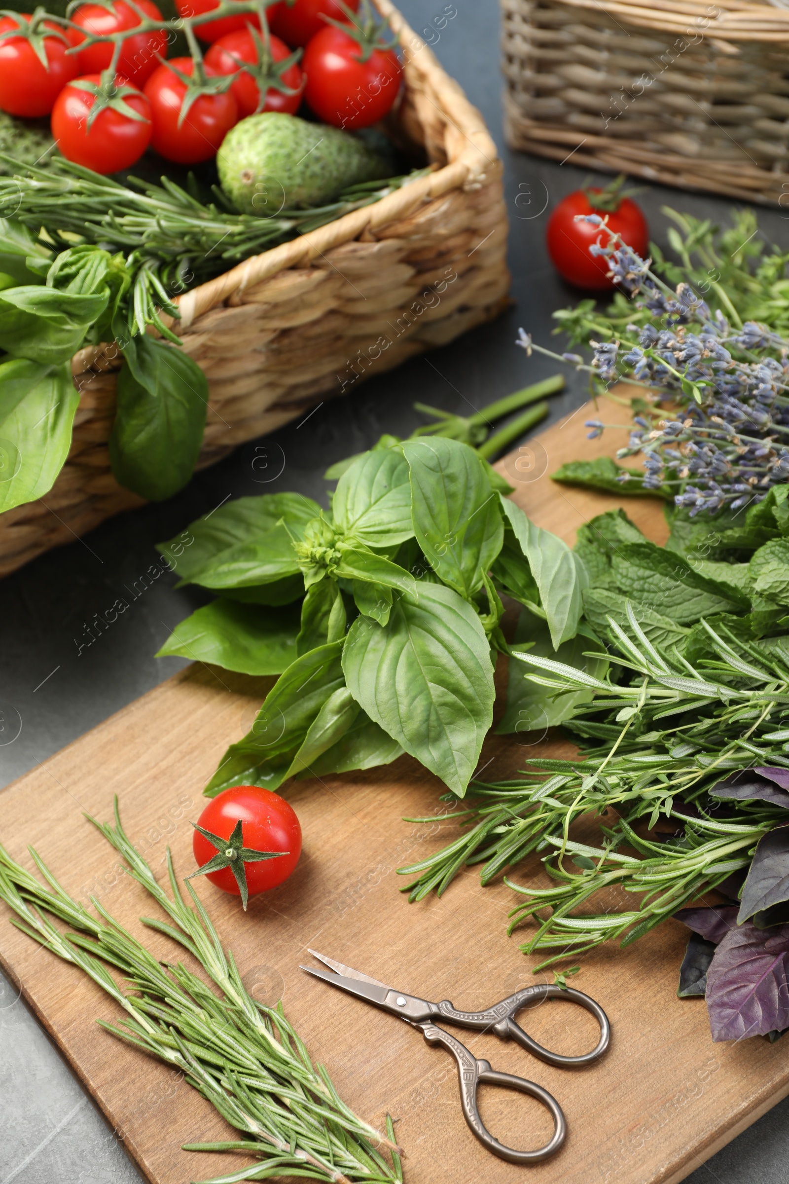 Photo of Different aromatic herbs, vegetables and scissors on gray table, closeup