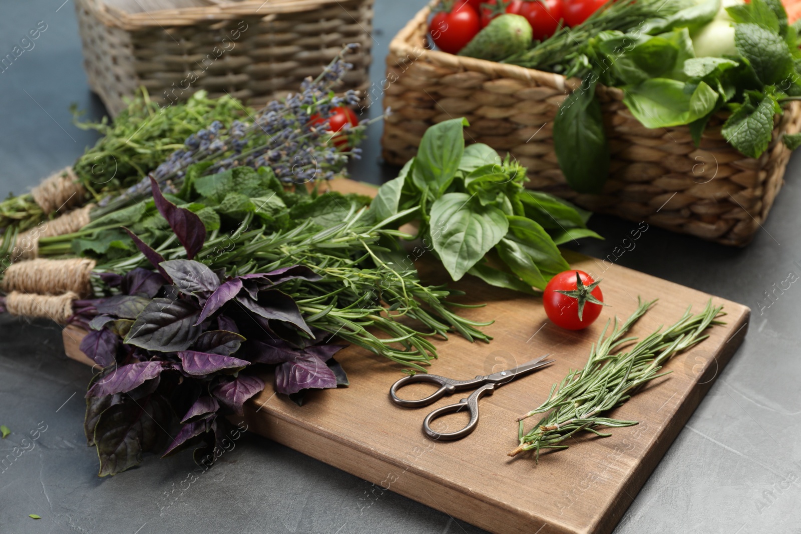 Photo of Different aromatic herbs, vegetables and scissors on gray table, closeup