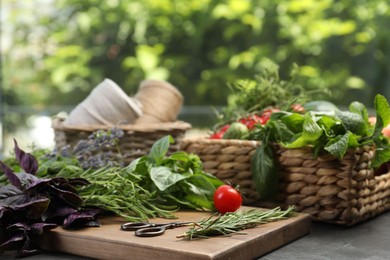 Different aromatic herbs, vegetables, scissors and threads on gray table, closeup