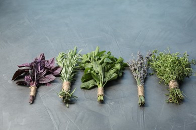 Photo of Bunches of different aromatic herbs on gray textured table