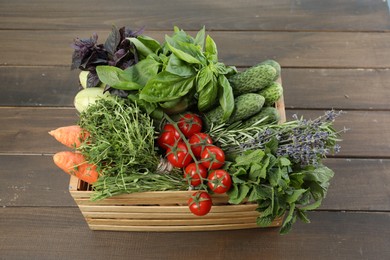 Different aromatic herbs and vegetables in crate on wooden table, above view